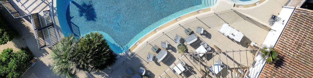Vue aérienne d'une piscine avec terrasse ombragée.