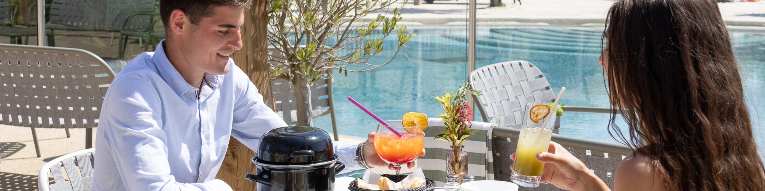 Couple buvant des cocktails en terrasse près d'une piscine.