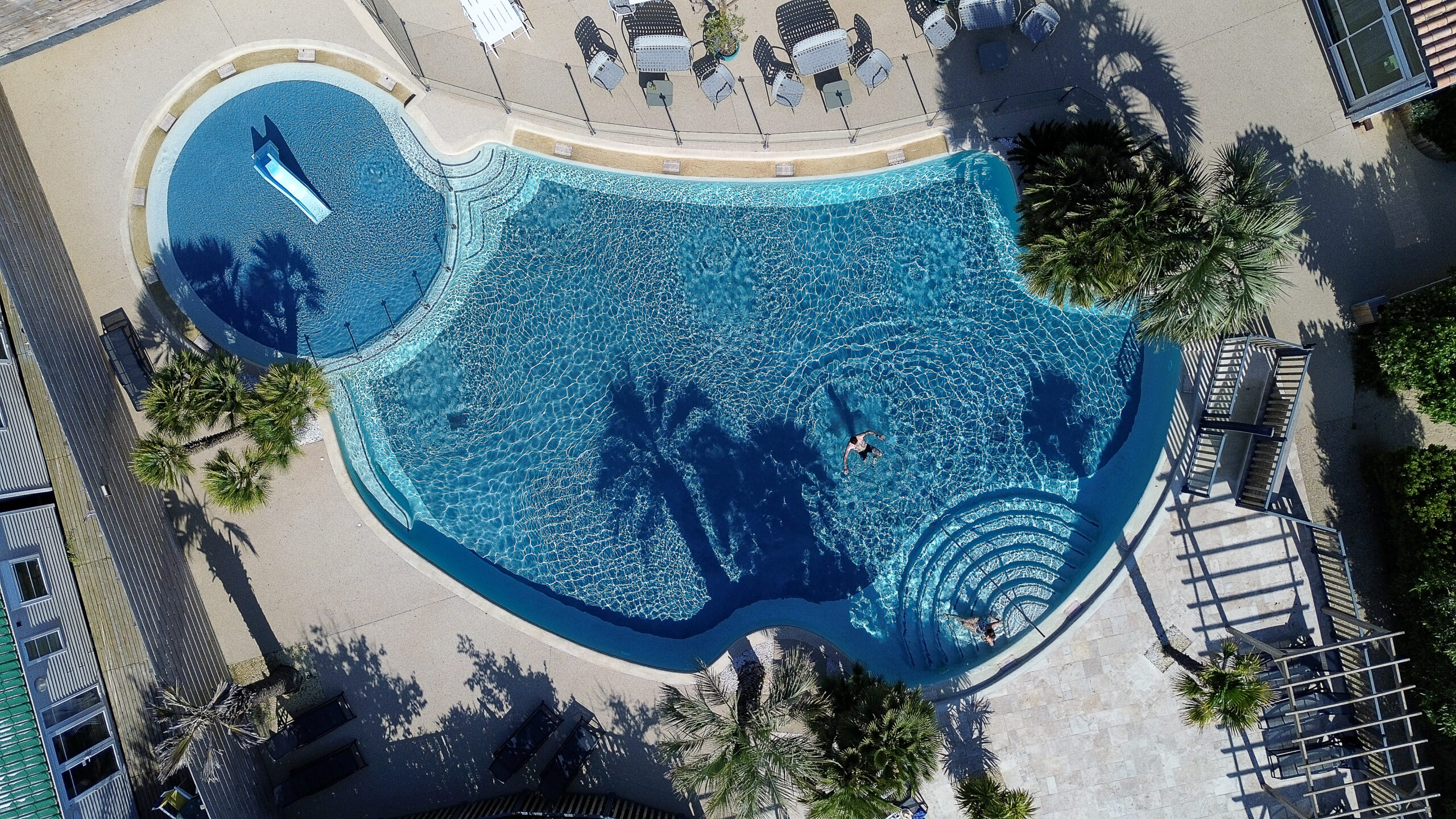 Vue aérienne d'une grande piscine et terrasse.