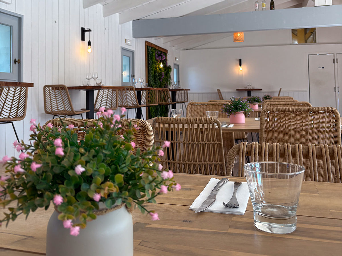 Intérieur d'un restaurant avec plantes et tables en rotin.