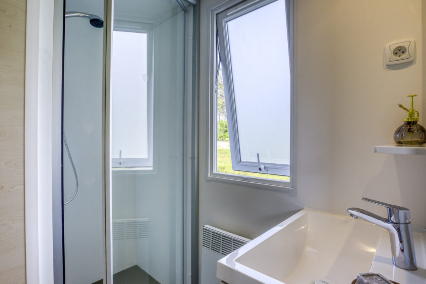 Salle de bain moderne avec douche et lavabo.