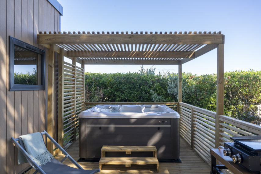 Jacuzzi en terrasse avec pergola en bois.