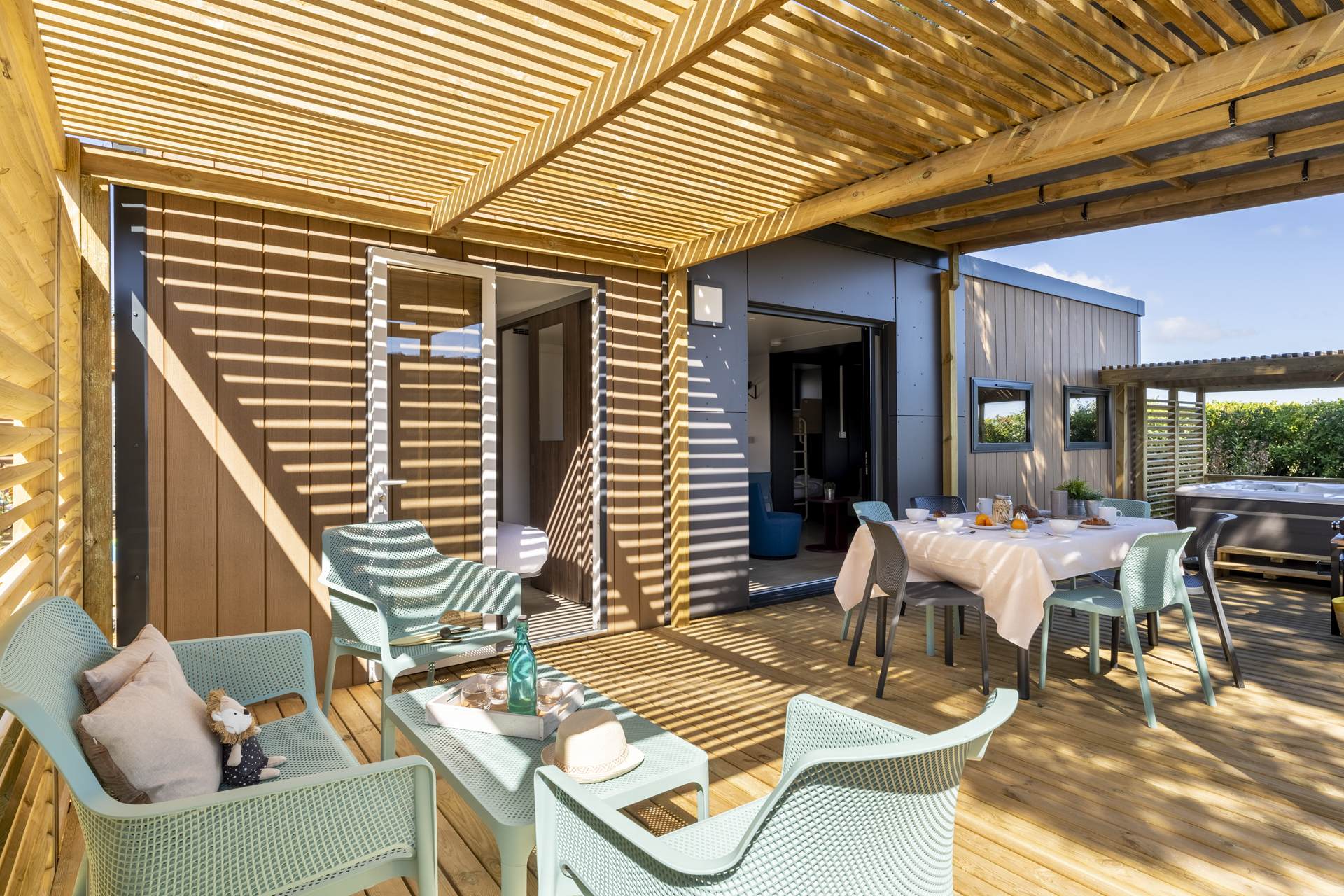 Terrasse en bois avec salon et table dressée.