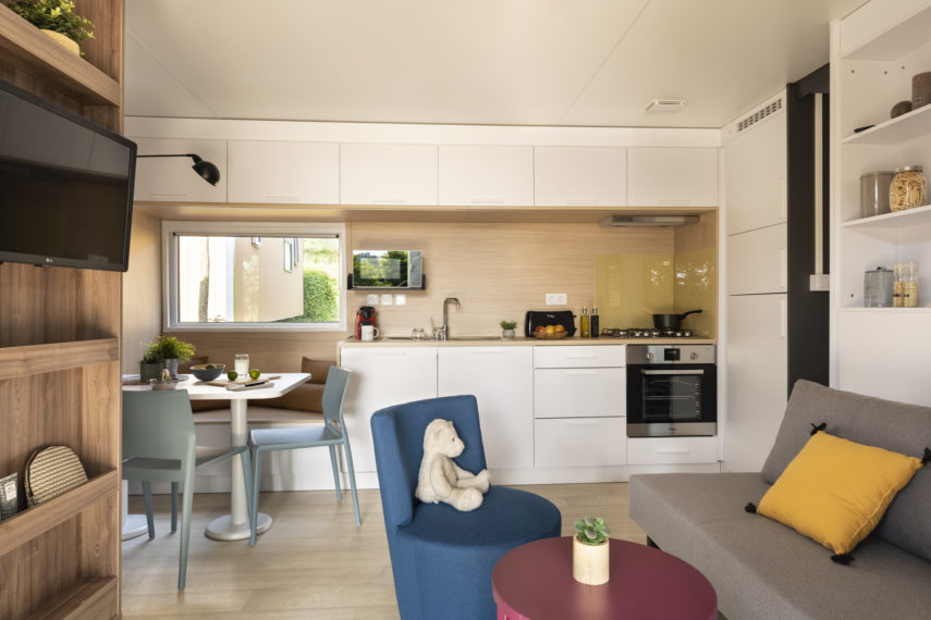 Cuisine moderne avec coin salon et peluche.