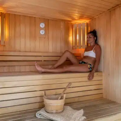Femme détendue assise dans un sauna en bois.