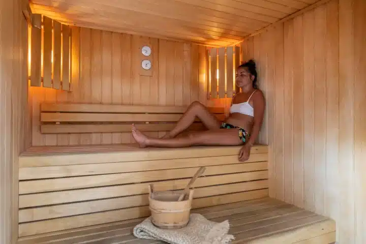 Femme détendue assise dans un sauna en bois.