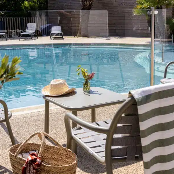 Piscine extérieure avec transats et chapeau de paille.
