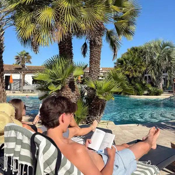 Personnes lisant au bord d'une piscine tropicale.