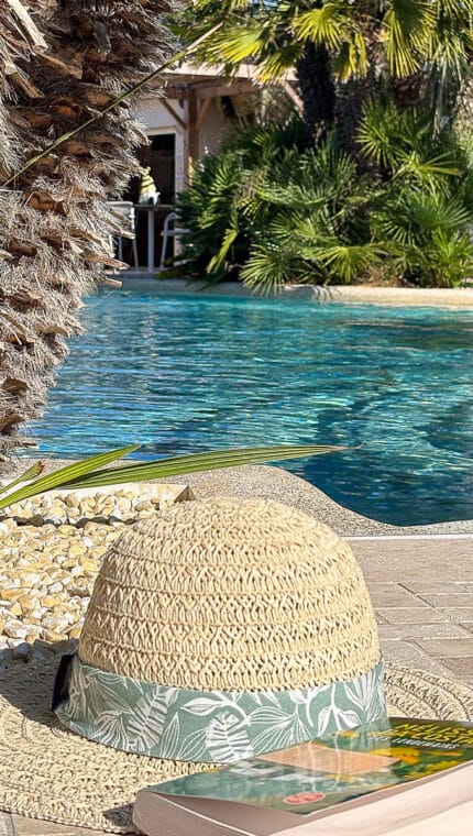 Chapeau et livre au bord de la piscine.