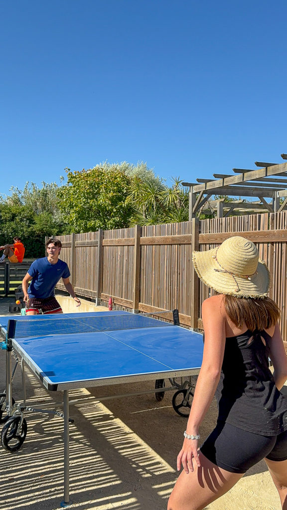 Deux personnes jouent au ping-pong en extérieur.